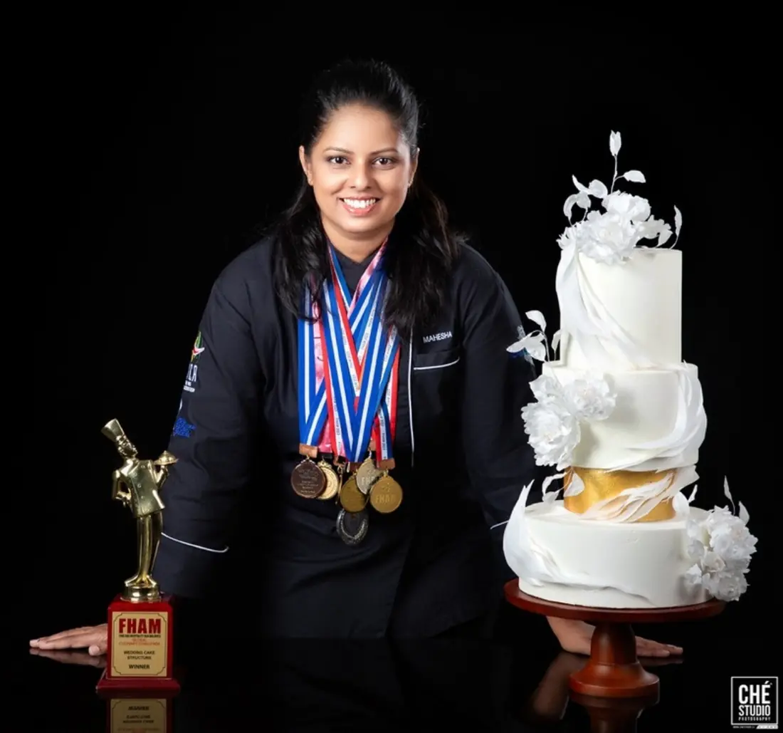 Mash wearing her competition medals beside a trophy and a white wedding cake